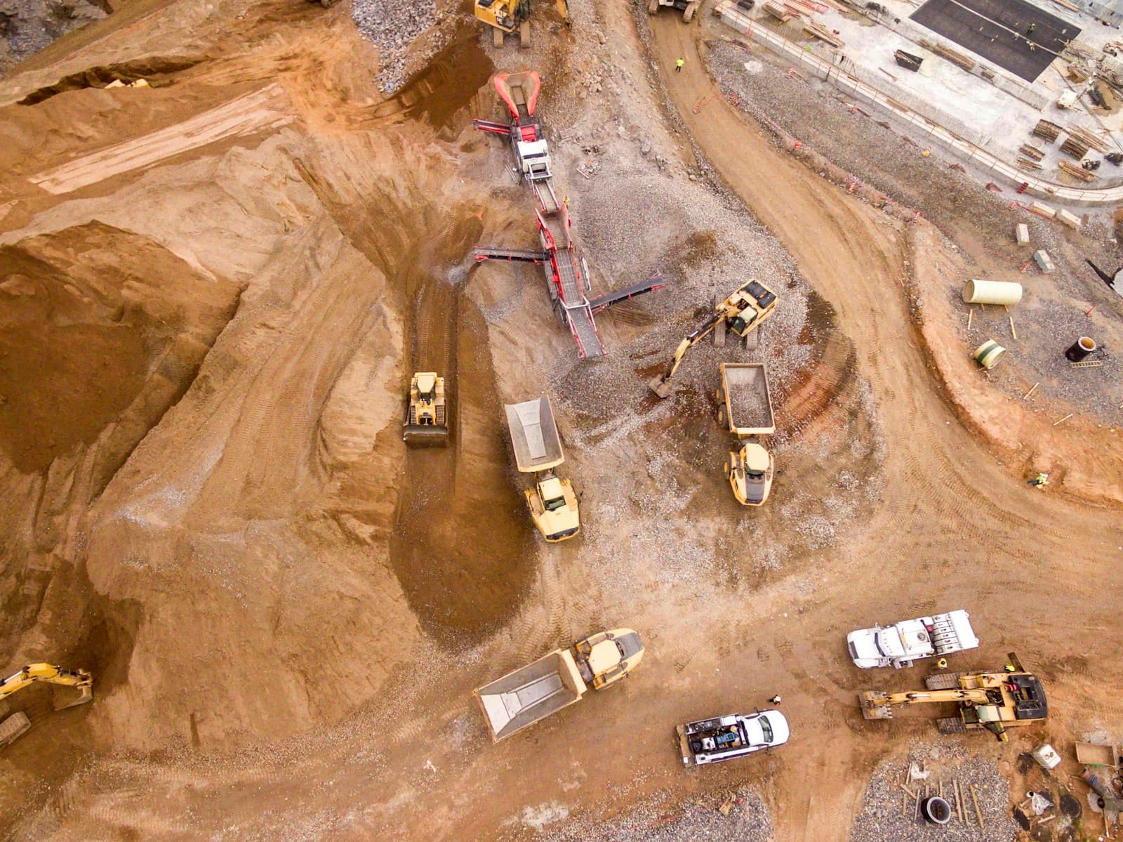 Aerial view of dump trucks on a large industrial earthworks or mining haul road.